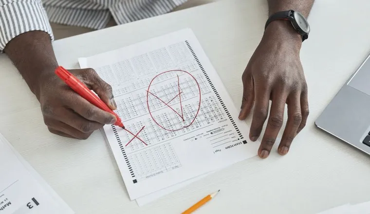 A hand marking a printed page with a red pen
