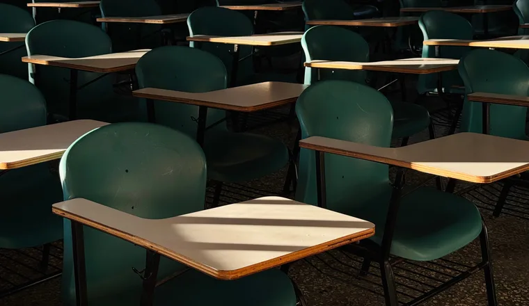 An empty classroom of sunlit desks, waiting