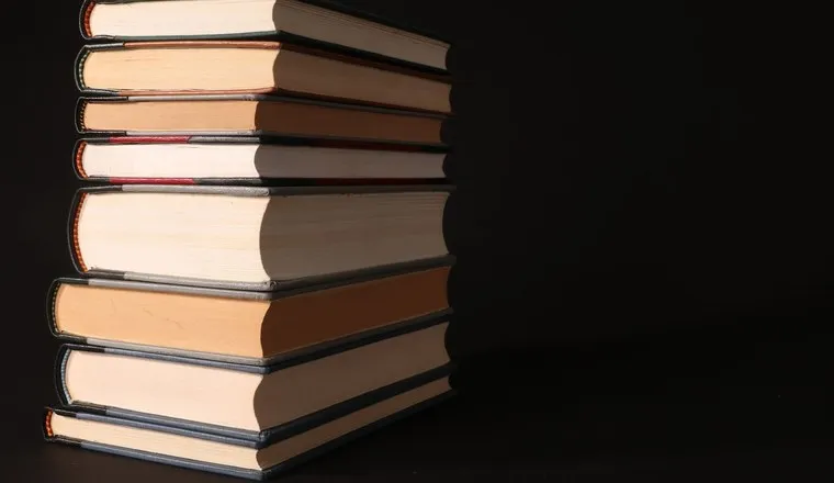 A stack of hardback books lit against a dark background
