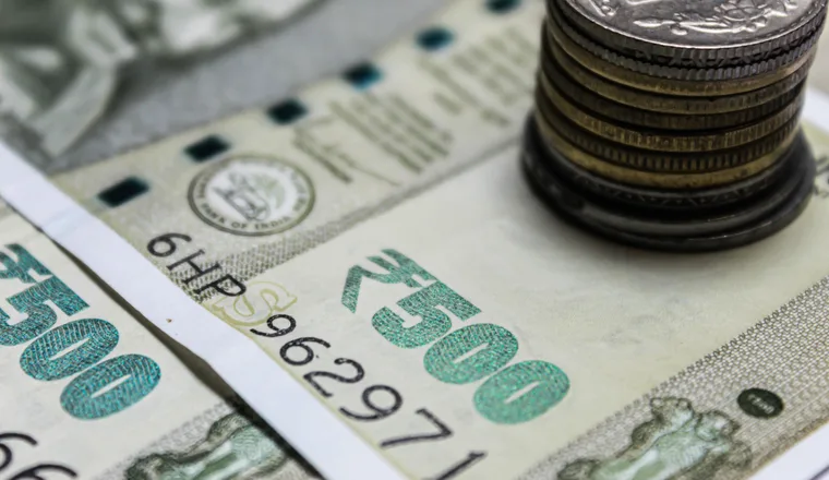 Indian banknotes and stacked coins on a dark surface